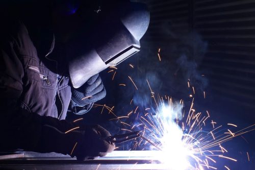 a worker welding steel together in the process of steel fabrication