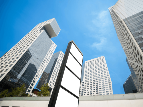 Blank signage board in front of tall commercial buildings